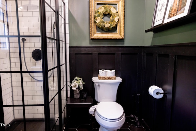 bathroom featuring toilet, a tile shower, and tile patterned floors