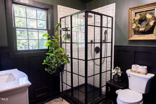 bathroom with a shower with door, vanity, and toilet