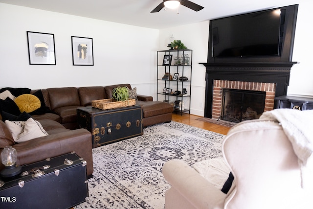 living room with a fireplace, ceiling fan, and light hardwood / wood-style floors