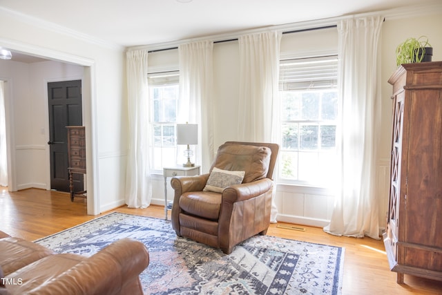 sitting room with crown molding and light hardwood / wood-style flooring