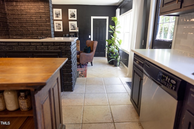 kitchen with light tile patterned floors, stainless steel dishwasher, wooden counters, and dark brown cabinetry