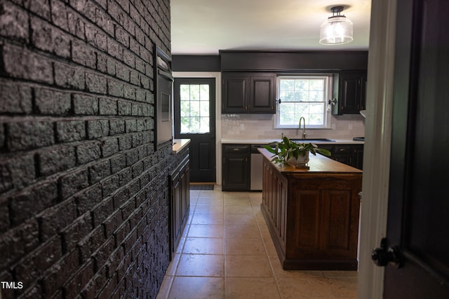 kitchen featuring brick wall, sink, decorative backsplash, and dark brown cabinets