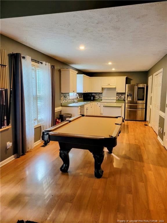 recreation room featuring pool table, light hardwood / wood-style floors, and a textured ceiling