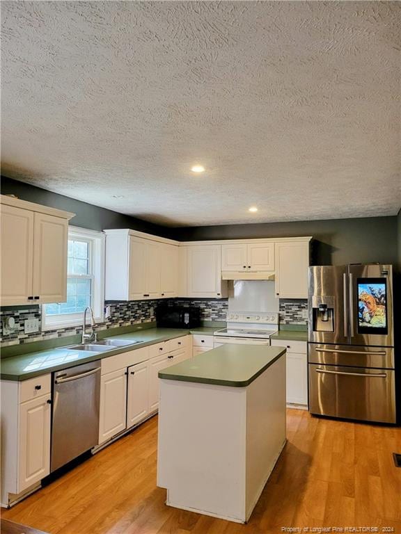 kitchen featuring a textured ceiling, appliances with stainless steel finishes, a center island, white cabinetry, and light wood-type flooring