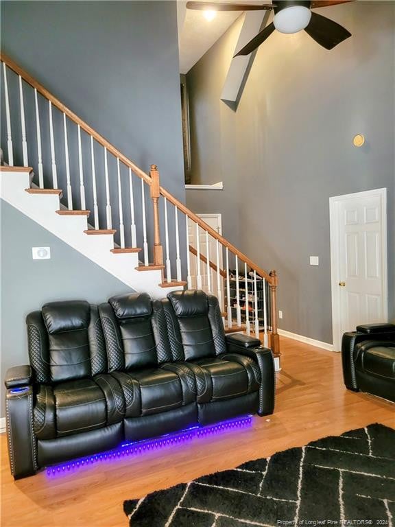 living room featuring ceiling fan, hardwood / wood-style flooring, and a high ceiling