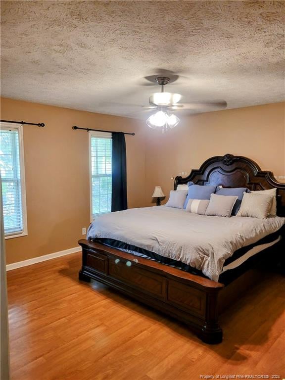 bedroom with ceiling fan, a textured ceiling, and light hardwood / wood-style flooring