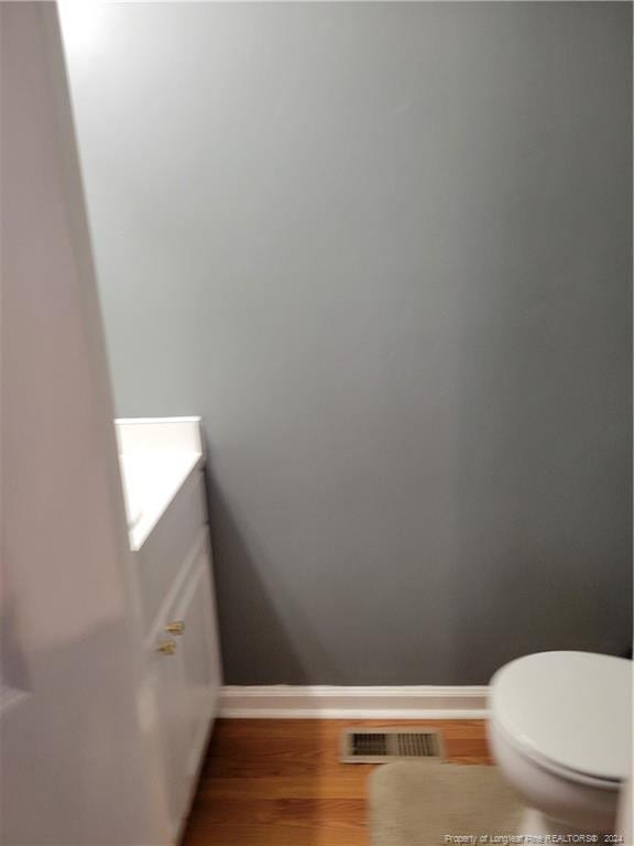 bathroom with vanity, toilet, and hardwood / wood-style flooring