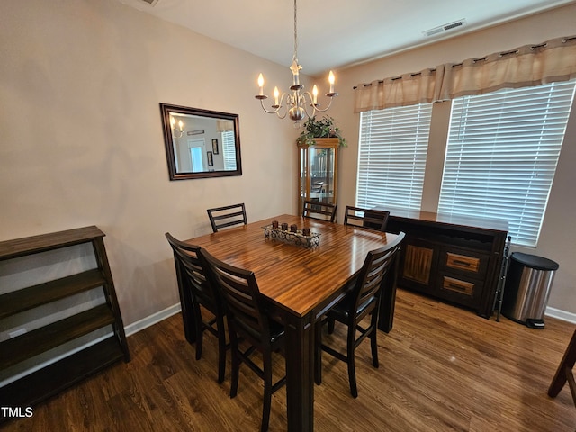 dining space with dark hardwood / wood-style flooring and a chandelier