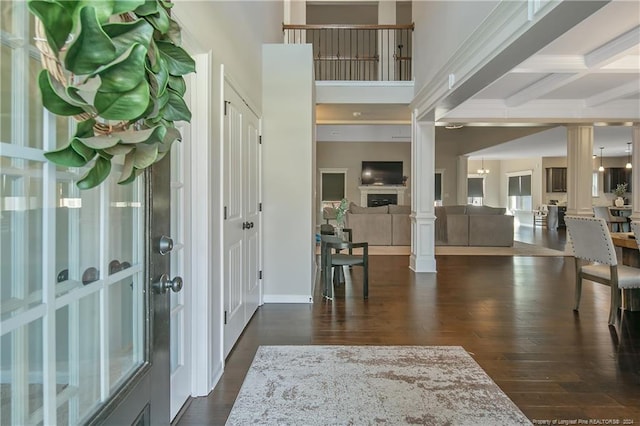 foyer entrance featuring coffered ceiling, beam ceiling, dark hardwood / wood-style flooring, and ornate columns