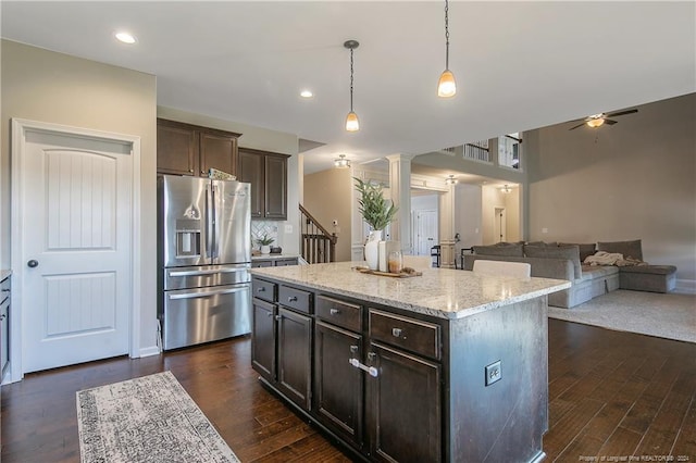 kitchen with a center island, dark hardwood / wood-style floors, ceiling fan, pendant lighting, and stainless steel fridge with ice dispenser