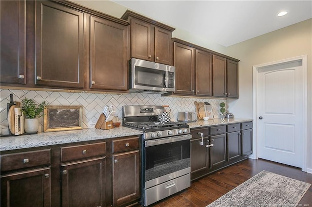 kitchen with light stone counters, stainless steel appliances, dark hardwood / wood-style flooring, and dark brown cabinetry