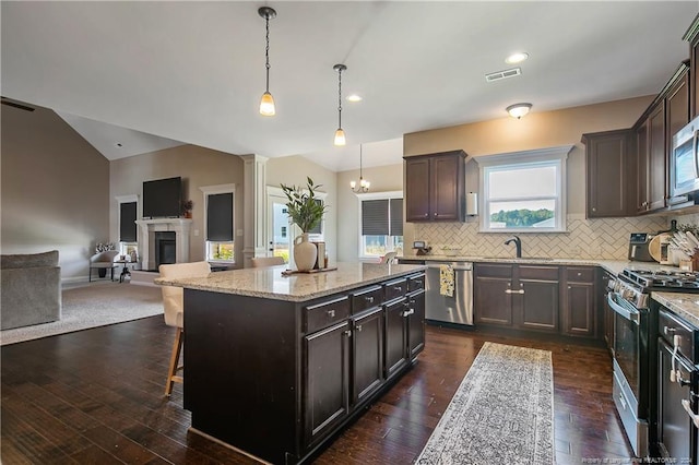 kitchen with hanging light fixtures, stainless steel appliances, dark hardwood / wood-style flooring, a center island, and a breakfast bar