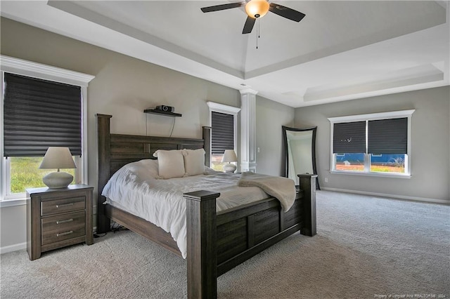 bedroom featuring a tray ceiling, ceiling fan, light colored carpet, and ornate columns