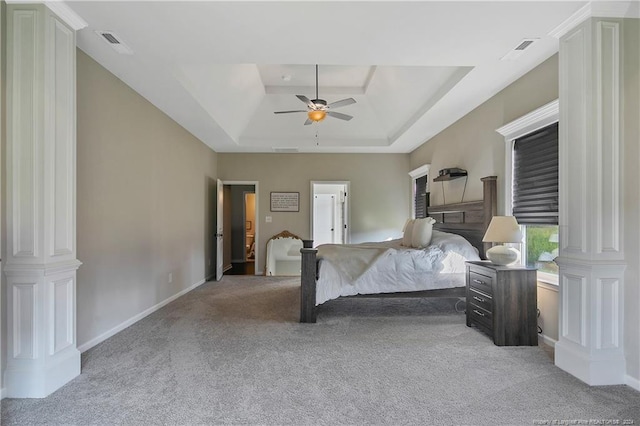 bedroom with a raised ceiling, ceiling fan, light colored carpet, and ornate columns