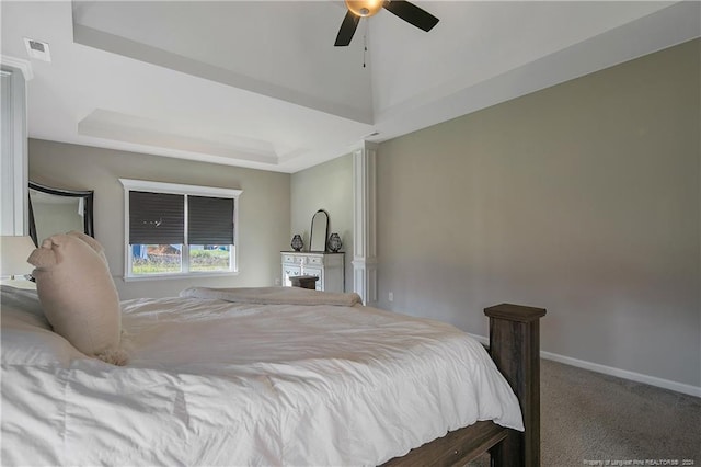 carpeted bedroom with a tray ceiling and ceiling fan