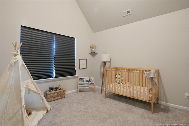 carpeted bedroom featuring vaulted ceiling and a crib