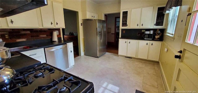 kitchen featuring decorative backsplash, white cabinets, range hood, and stainless steel appliances