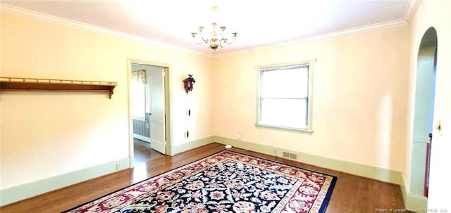 empty room featuring radiator, crown molding, hardwood / wood-style floors, and an inviting chandelier