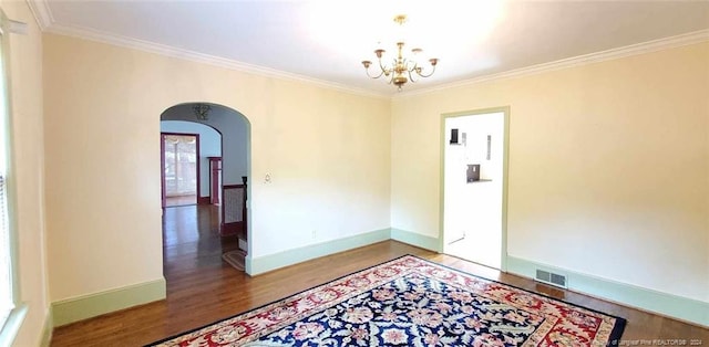 empty room featuring wood-type flooring, crown molding, and a notable chandelier