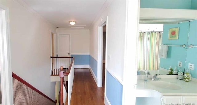 corridor with dark hardwood / wood-style floors, crown molding, and sink