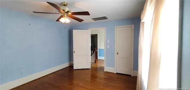 unfurnished bedroom featuring ceiling fan and dark hardwood / wood-style flooring