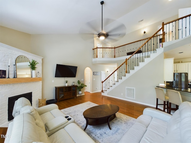 living room with a fireplace, high vaulted ceiling, hardwood / wood-style flooring, and ceiling fan