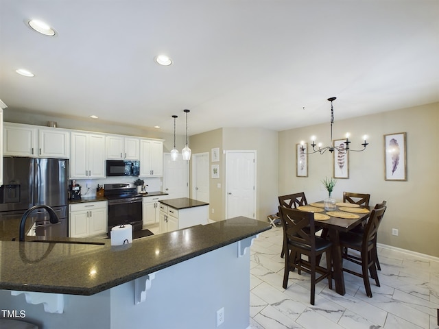 kitchen featuring white cabinets, a notable chandelier, black appliances, pendant lighting, and a breakfast bar