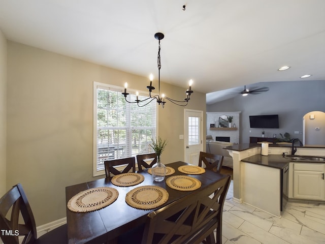 dining area with lofted ceiling, sink, and ceiling fan with notable chandelier