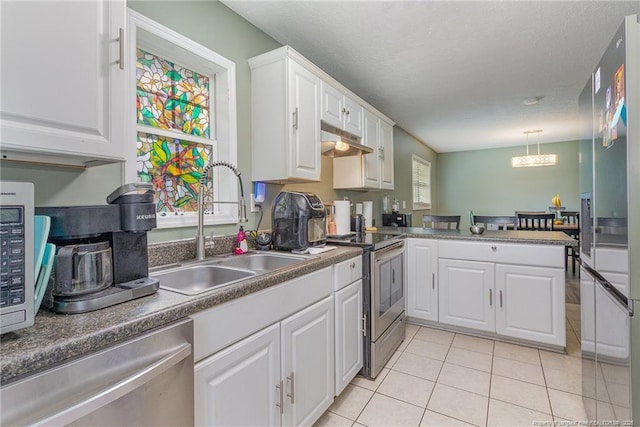 kitchen with decorative light fixtures, sink, white cabinets, light tile patterned floors, and stainless steel appliances