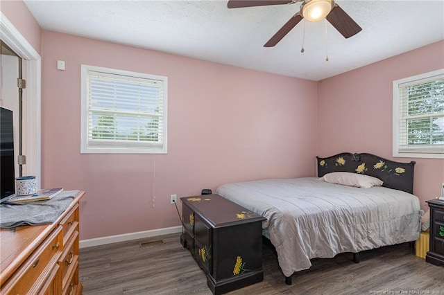 bedroom featuring multiple windows, dark wood-type flooring, and ceiling fan