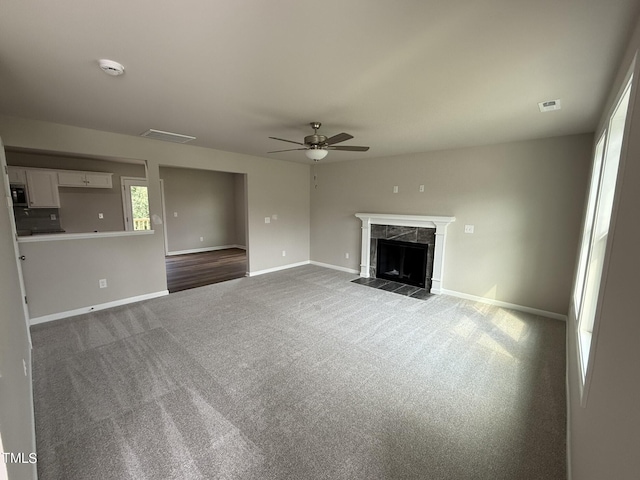 unfurnished living room with carpet, a high end fireplace, and ceiling fan