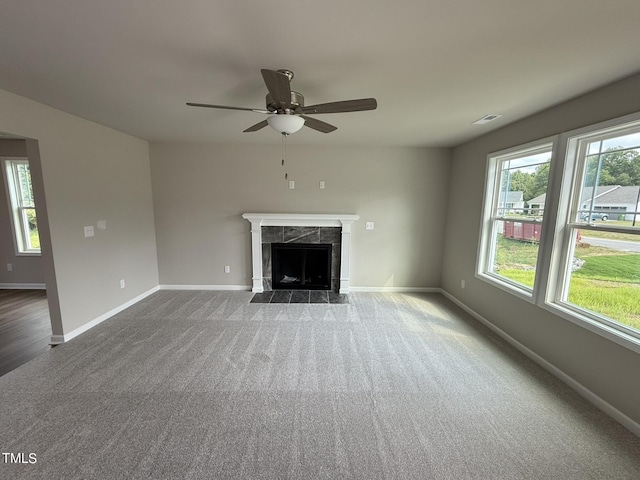 unfurnished living room with a fireplace, dark carpet, and ceiling fan