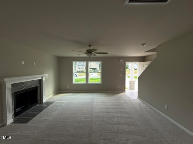 unfurnished living room with ceiling fan, a premium fireplace, and carpet