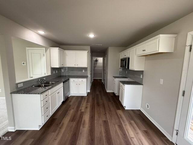 kitchen with appliances with stainless steel finishes, tasteful backsplash, white cabinets, dark hardwood / wood-style flooring, and sink