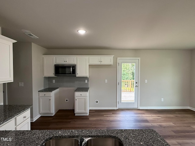 kitchen with dark stone counters, white cabinets, backsplash, and dark hardwood / wood-style flooring