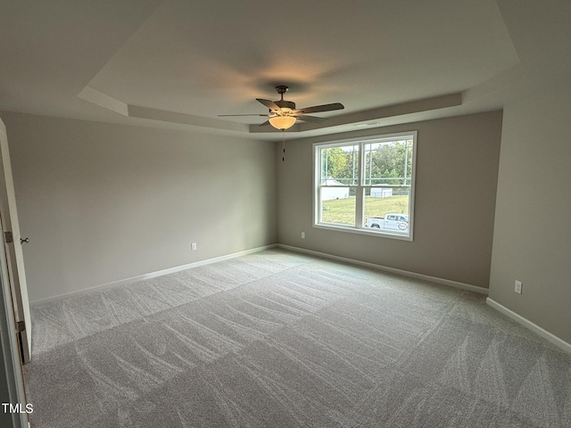 carpeted spare room featuring a tray ceiling and ceiling fan