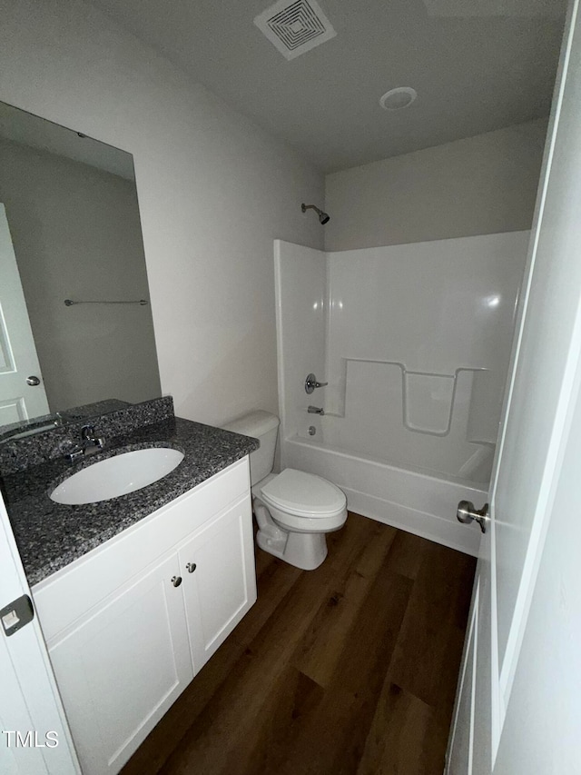 full bathroom featuring hardwood / wood-style floors, vanity, toilet, and bathtub / shower combination