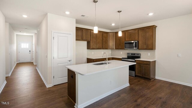 kitchen with appliances with stainless steel finishes, sink, dark hardwood / wood-style floors, and a kitchen island with sink