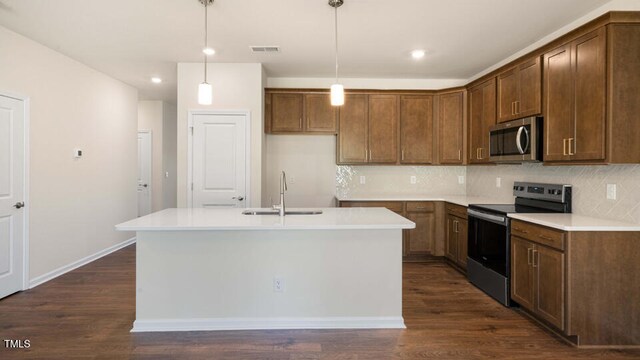 kitchen featuring sink, a kitchen island with sink, dark hardwood / wood-style floors, pendant lighting, and appliances with stainless steel finishes