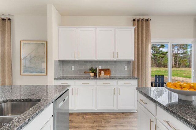 kitchen with white cabinets, dark stone counters, and light hardwood / wood-style flooring