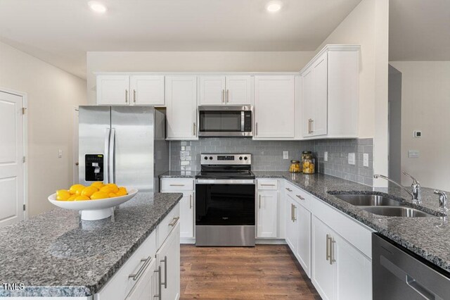 kitchen with dark stone countertops, white cabinetry, sink, dark hardwood / wood-style floors, and appliances with stainless steel finishes