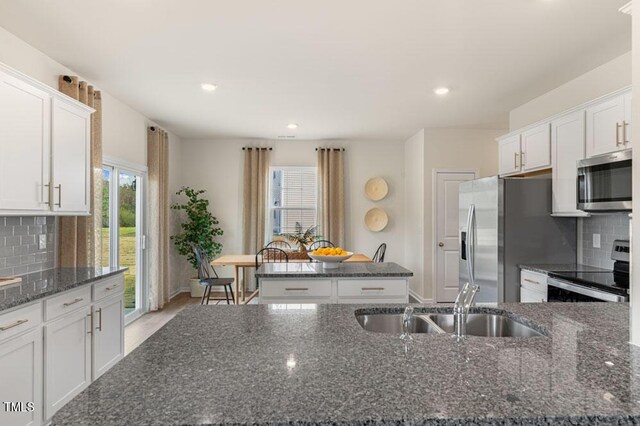 kitchen featuring a wealth of natural light, appliances with stainless steel finishes, dark stone counters, and white cabinets