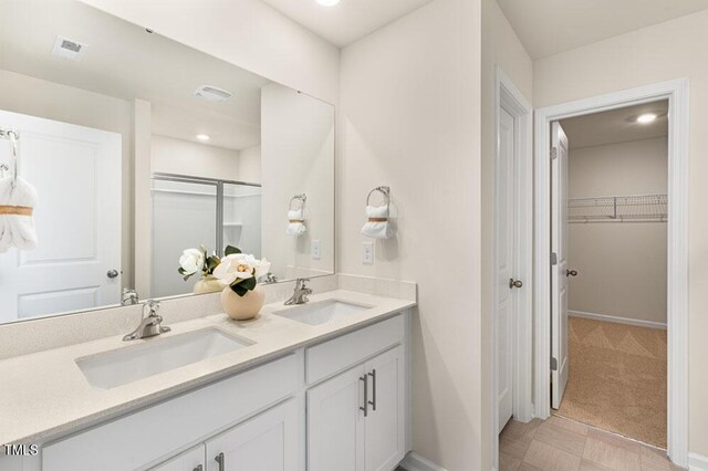 bathroom featuring a shower with door and vanity