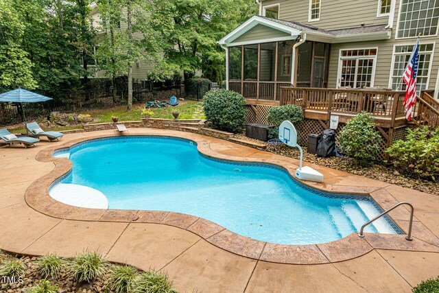 view of swimming pool featuring a wooden deck, a patio, and a sunroom