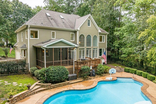 rear view of property featuring a sunroom, a patio, and a pool side deck