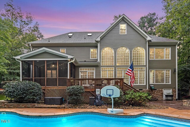 back house at dusk featuring central AC unit, a sunroom, a patio, and a swimming pool side deck