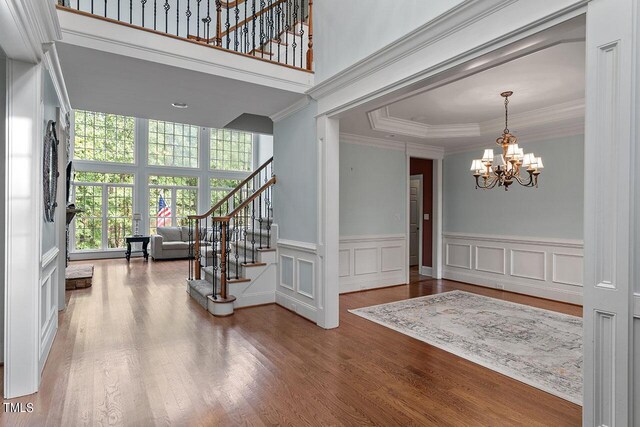 entryway with crown molding, a high ceiling, an inviting chandelier, and hardwood / wood-style flooring