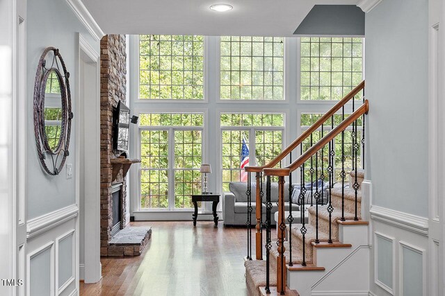 interior space with ornamental molding, wood-type flooring, and a stone fireplace