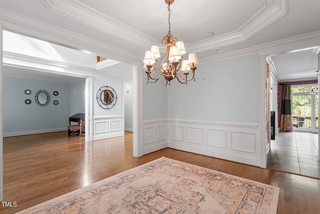 unfurnished room with an inviting chandelier, crown molding, and hardwood / wood-style floors