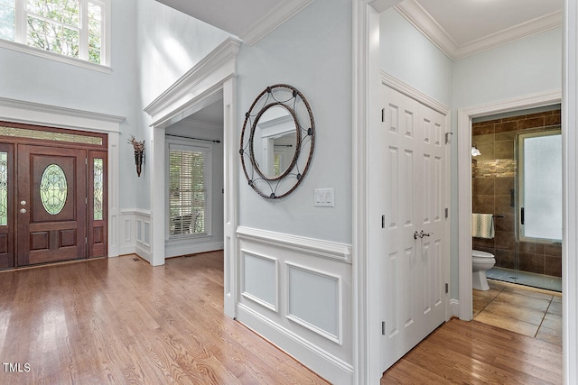 foyer with ornamental molding, light wood-type flooring, and a wealth of natural light